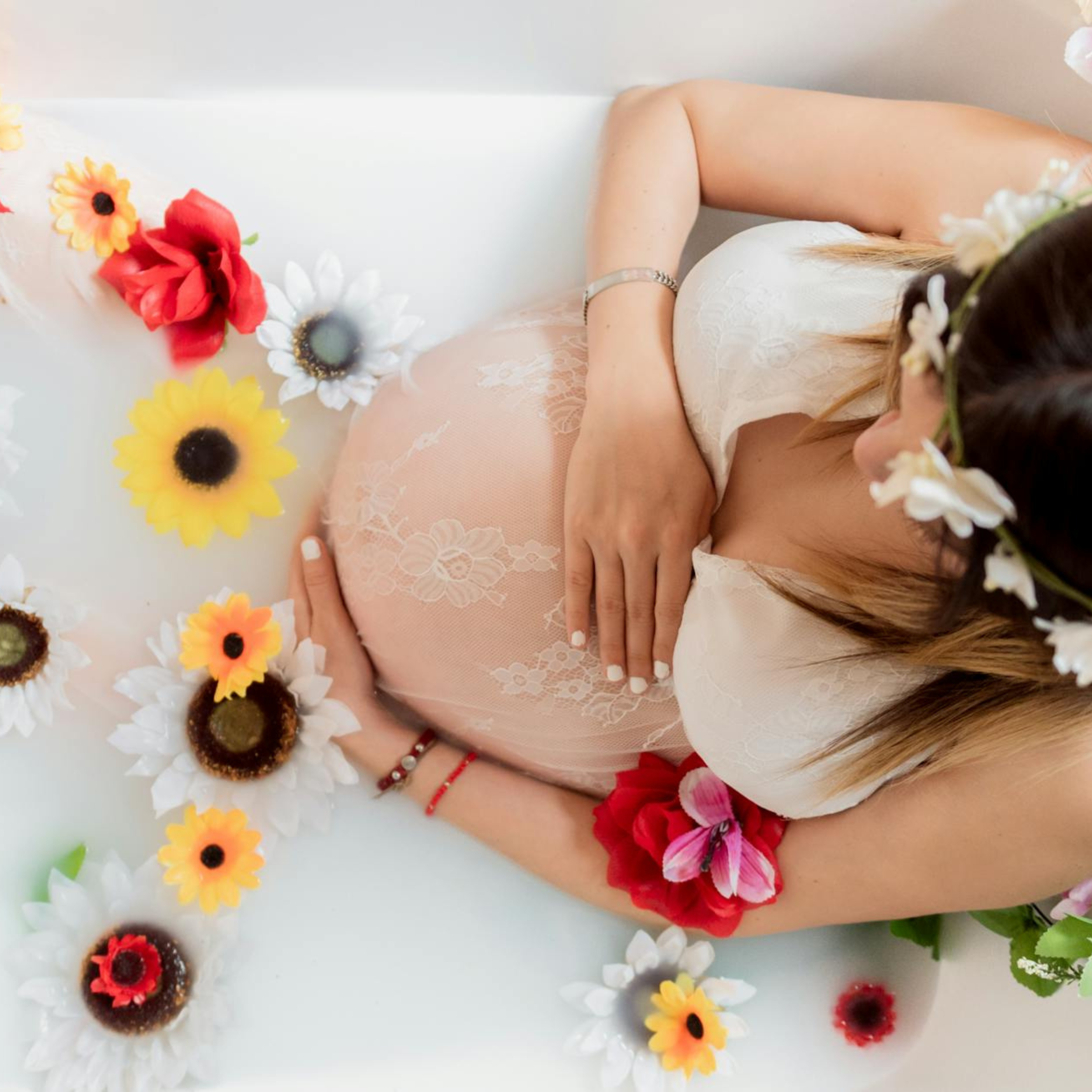 high angle shot of a pregnant woman sitting in a bathtub with flowers